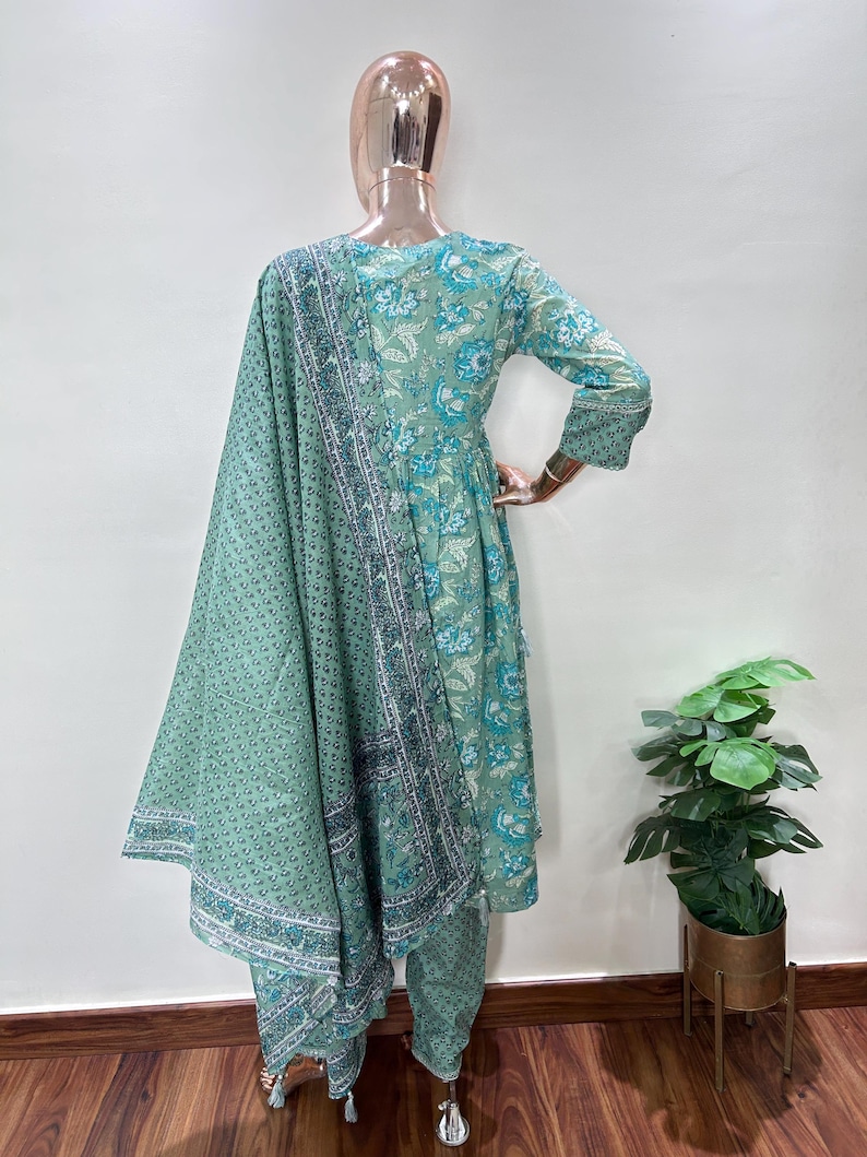 May include: A mint green floral print salwar kameez set. The ensemble includes a long-sleeved tunic, matching pants, and a patterned scarf. The tunic and pants feature a repeating floral pattern in shades of blue and white.