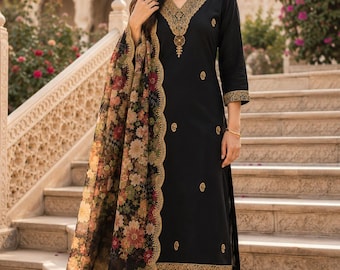 May include: A black long-sleeved tunic with gold embroidery around the V-neckline, cuffs, and hem, paired with matching black trousers. A sheer black dupatta features a colourful floral print and a scalloped gold embroidered border edge.
