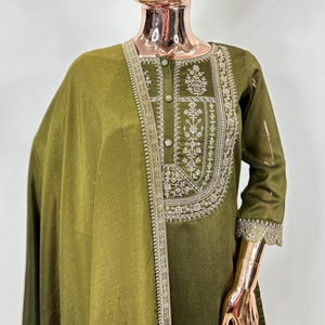 May include: A green kurta with silver embroidery and a matching dupatta. The kurta has a button-up front and three-quarter sleeves. The dupatta is sheer and has a delicate border.
