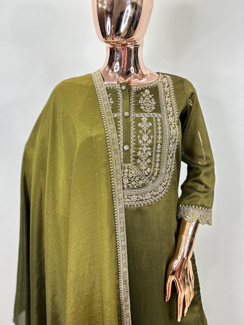 May include: A green kurta with silver embroidery and a matching dupatta. The kurta has a button-up front and three-quarter sleeves. The dupatta is sheer and has a delicate border.