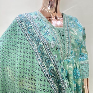 May include: A light green floral print dress with a matching scarf. The dress features a square neckline and long sleeves. The scarf and dress have a repeating pattern of white and teal floral designs.