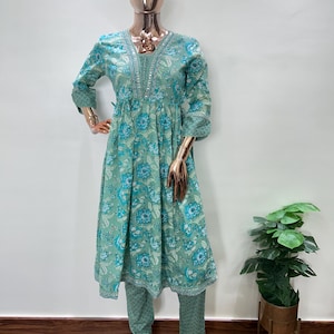 May include: A mint green floral print kurta set on a mannequin. The set includes a long-sleeved tunic with a V-neck and matching pants. The floral pattern features blue and white flowers. The mannequin has a gold-colored head and hands.