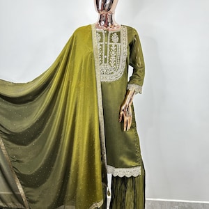 May include: A green embroidered kurta with a matching dupatta and palazzo pants. The kurta has a round neckline and three-quarter sleeves. The dupatta is sheer and has a gold border. The palazzo pants are pleated and have a lace trim.