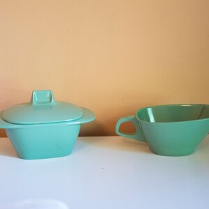 May include: A set of two vintage turquoise ceramic serving dishes. The larger dish has a lid and the smaller dish has a handle.
