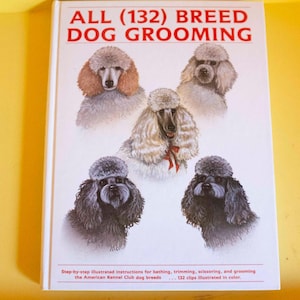 May include: A book titled "ALL (132) BREED DOG GROOMING" features illustrations of various poodle breeds. The cover displays multiple poodle portraits with different coat colours and styles. The book provides step-by-step instructions for grooming.
