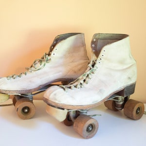 Patins à roulettes blancs antiques des années 50 avec des roues en bois : décor d&#39;affichage
