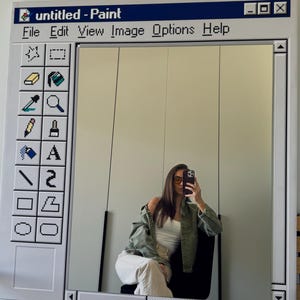 Könnte beinhalten: Ein großer, rechteckiger Spiegel, der so gestaltet ist, dass er wie die Windows Paint Programmoberfläche aussieht. Der weiße Rahmen hat eine blaue Kopfzeile mit dem Text "untitled - Paint". Der Spiegel spiegelt eine Person wider.