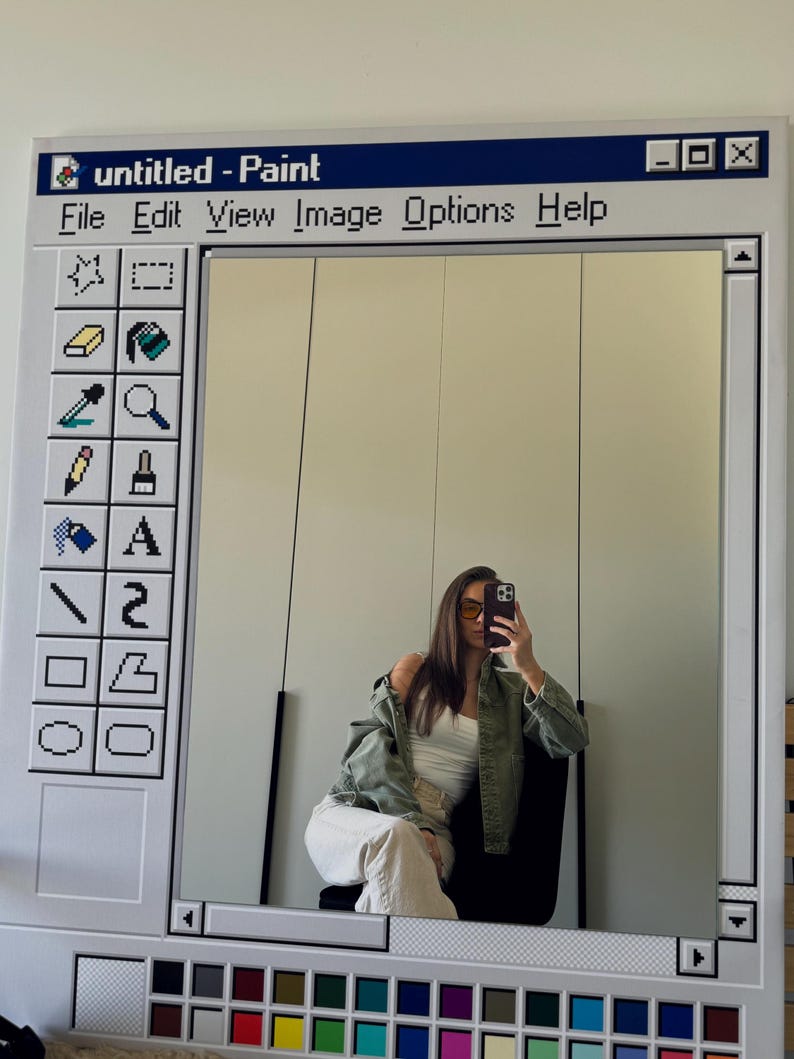 May include: A large, rectangular mirror framed to resemble the classic Windows Paint program interface. The frame is white with a blue header bar that reads "untitled - Paint". The mirror reflects a person.