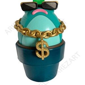 May include: A whimsical teal-colored cactus figurine wearing black sunglasses, a gold chain necklace, and a gold dollar sign pendant. The cactus has a pink mouth and a green leaf on top, and sits in a teal pot.