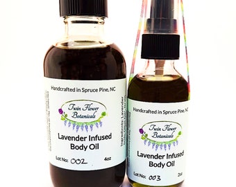 May include: Two glass bottles of lavender infused body oil. The larger bottle is 4 oz and the smaller bottle is 2 oz. Both bottles have a black cap and a white label with the text "Twin Flower Botanicals" and "Lavender Infused Body Oil". The larger bottle has the lot number 002 and the smaller bottle has the lot number 003.