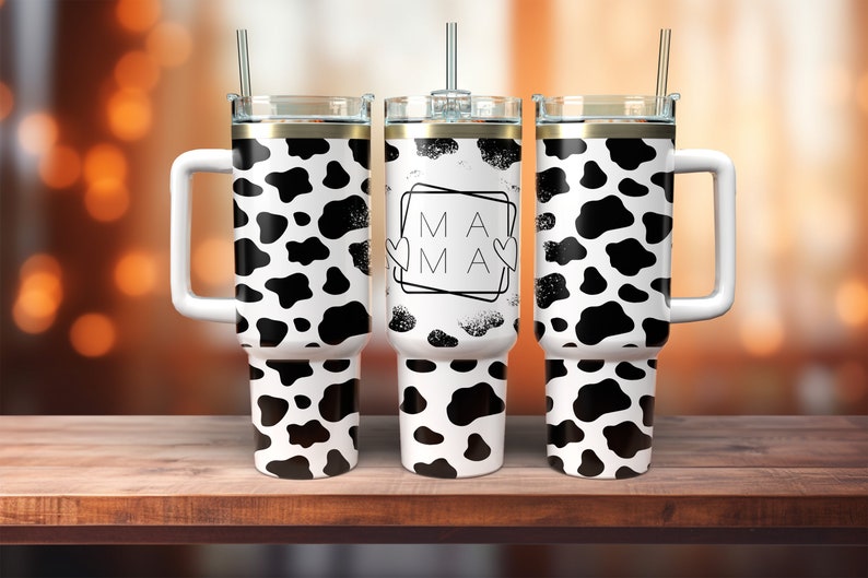 May include: Three stainless steel tumblers with a cow print design. The center tumbler has the word "MAMA" in a black frame with two hearts.