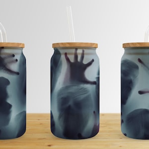May include: Three glass tumblers with wooden lids and clear straws. Each tumbler features a ghostly image of a hand and face.