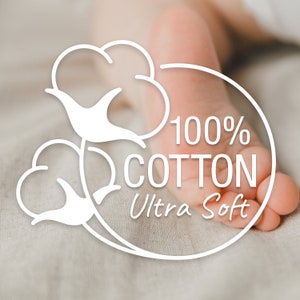 K&ouml;nnte beinhalten: Eine wei&szlig;e grafische &Uuml;berlagerung mit zwei Baumwollbl&uuml;ten-Illustrationen und dem Text 100% COTTON Ultra Soft, platziert &uuml;ber einer unscharfen Ansicht eines kleinen Fu&szlig;es. Das Design verwendet klare wei&szlig;e Linien und Typografie f&uuml;r die Qualit&auml;t.