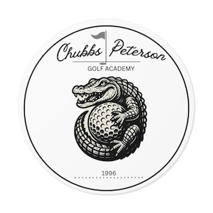 May include: A circular white sticker with a black outline. It displays a detailed black and white illustration of an alligator clutching a golf ball. The text "Chubbs Peterson Golf Academy" is above, and "1996" is below the alligator.