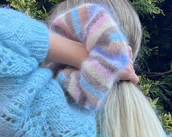 May include: A light blue fuzzy knit sweater with a colorful striped pattern on the shoulder.