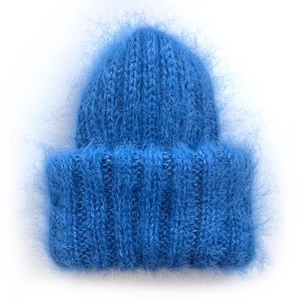 May include: A vibrant blue beanie hat with a soft, fuzzy texture. The hat is knitted with a ribbed brim and a rounded crown. The color is a bright, solid blue, and the hat appears to be made of a warm, cozy material.
