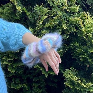 May include: A fuzzy, multi-colored knit wrist warmer with stripes of pink, blue, and brown.
