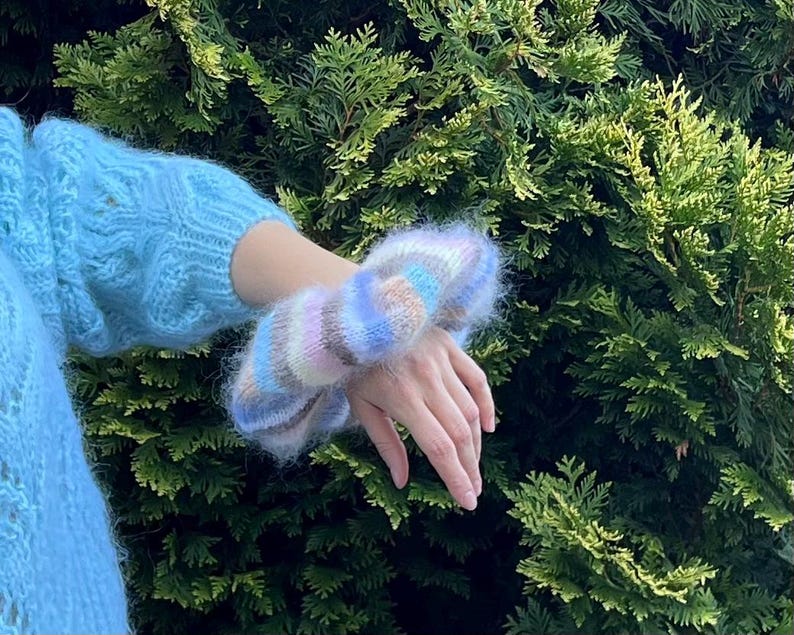 May include: A fuzzy, multi-colored knit wrist warmer with stripes of pink, blue, and brown.