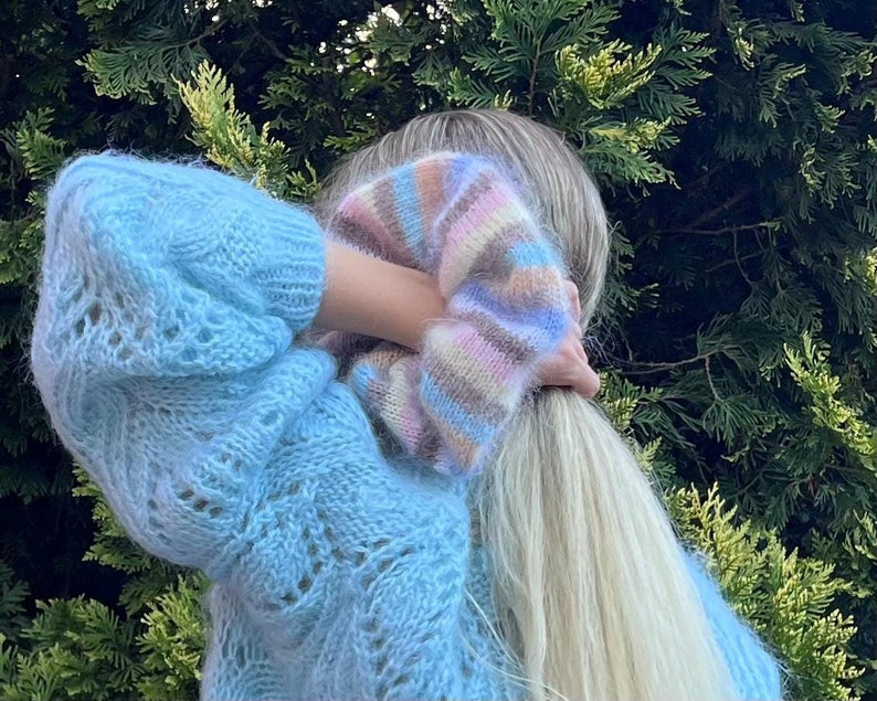 May include: A light blue fuzzy knit sweater with a colorful striped pattern on the shoulder.