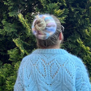 May include: A light blue knitted sweater with a delicate openwork pattern. The sweater is soft and fluffy, with a slightly fuzzy texture.
