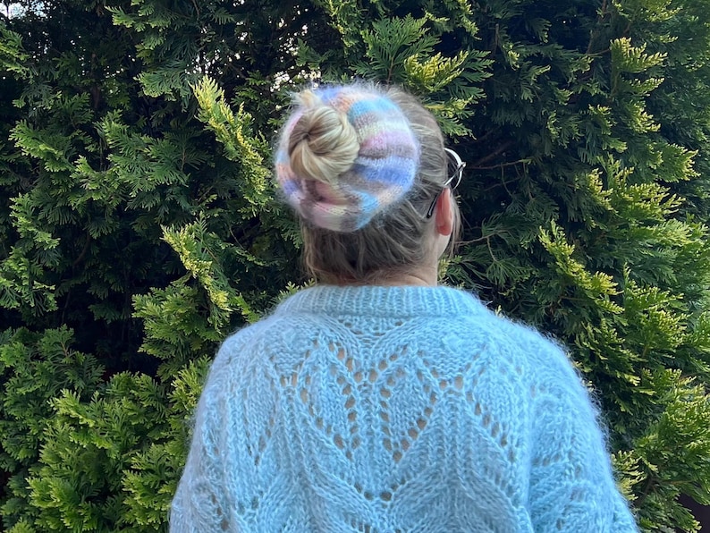 May include: A light blue knitted sweater with a delicate openwork pattern. The sweater is soft and fluffy, with a slightly fuzzy texture.