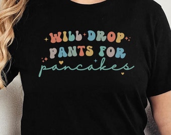 May include: Black t-shirt with the text "Will Drop Pants For Pancakes" in rainbow colors.