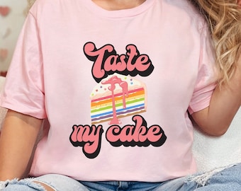 May include: A pink t-shirt with a rainbow cake graphic and the text "Taste my cake" in a retro font.