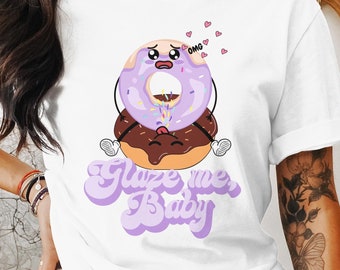May include: White t-shirt with a cartoon donut with purple icing and sprinkles. The donut has a face and says "OMG". The text "Glaze me, Baby" is written in purple below the donut.