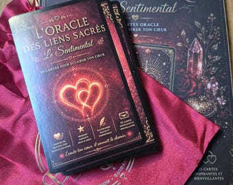 May include: A deck of oracle cards titled L'Oracle des Liens Sacrés Le Sentimental with a red heart graphic, resting on a matching dark box and a magenta drawstring pouch. The box features the text L'Oracle des Liens Sacrés Sentimental.