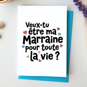 Puede incluir: Una tarjeta de felicitación blanca con el texto en negro Veux-tu être ma Marraine pour toute la vie? La tarjeta está decorada con pequeños corazones dibujados a mano en tonos rojo, azul y amarillo, sobre un fondo de color azul brillante.