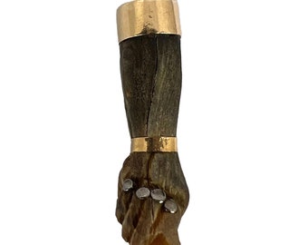 May include: A gold pendant featuring a carved wooden hand with a gold band around the wrist and four silver studs on the fingers.