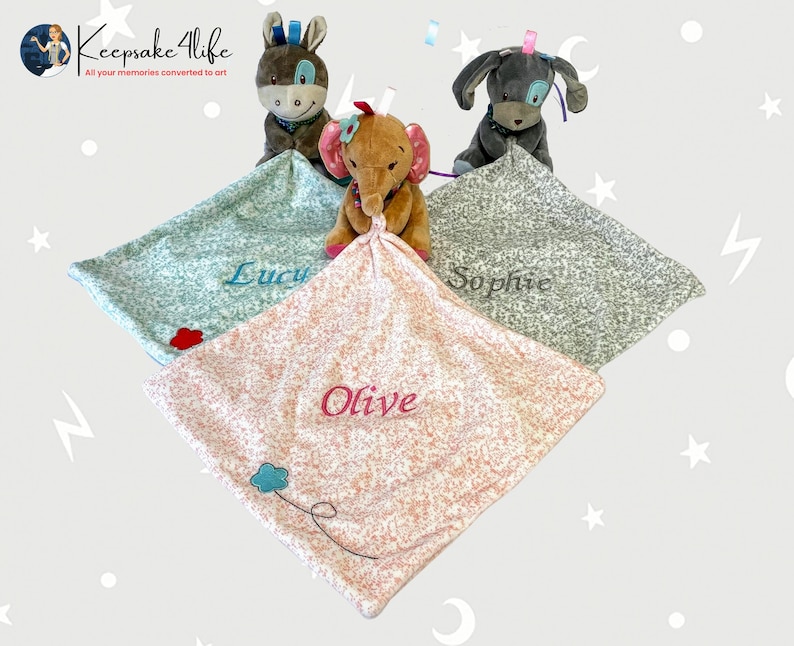 May include: Three personalised baby blankets with embroidered names, Lucy, Sophie, and Olive. Each blanket features a different colour and pattern, and is paired with a plush animal toy. The toys are a donkey, a dog, and an elephant.
