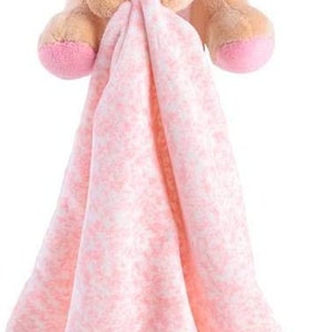 May include: A pink and brown plush elephant toy with a pink and white blanket attached. The elephant has a pink flower on its head and a pink and purple scarf around its neck.