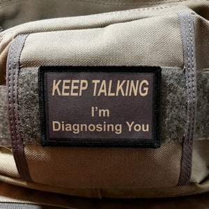 May include: A brown patch with black stitching and the text "KEEP TALKING I'm Diagnosing You" in yellow.