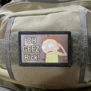 May include: A tan tactical backpack with a black patch featuring a cartoon character with the text "OH GEEZ, Rick!"