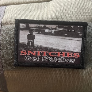 May include: Black and white patch with the text "SNITCHES Get Stitches" in red and white. The patch features a black and white image of a person standing in front of a car.