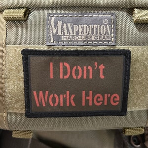 May include: A green Maxpedition backpack with a black patch that says "I Don't Work Here" in red letters.