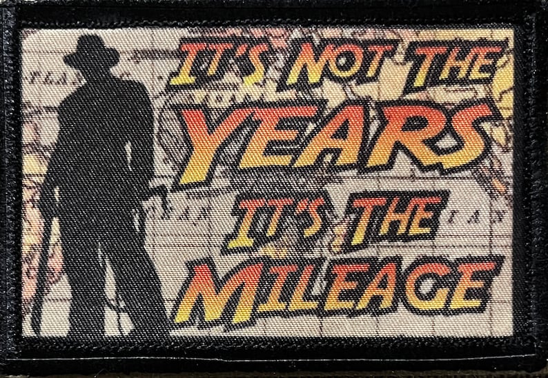 May include: A black and white patch with a silhouette of a person in a hat and the text "It's not the years, it's the mileage" in yellow and orange.