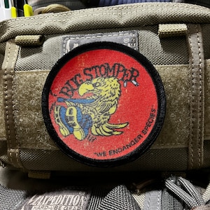 May include: A red and black circular patch with a yellow bird illustration and the text "Big Stomper - We Endanger Species".
