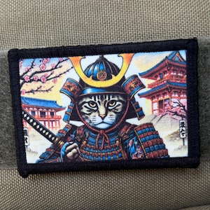 Könnte beinhalten: Ein schwarz-weißes Patch mit einer Katze, die als Samurai-Krieger verkleidet ist. Die Katze trägt einen Helm mit einem goldenen Wappen und hält ein Schwert. Der Hintergrund ist eine farbenfrohe Szene mit einem japanischen Tempel und Kirschblüten.