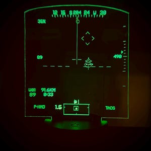 Peut inclure: Un affichage numérique vert avec une cible au centre et une portée de 91,6 km. L'affichage affiche également un cap de 0:33 et un P-HMD de 1,5. L'affichage est intitulé "TADS".