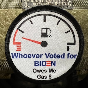 May include: A white round patch with a black border. The patch features a gas gauge with a red needle pointing to empty. The text "Whoever Voted for BIDEN Owes Me Gas $" is printed below the gauge.