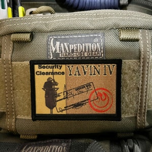 May include: A green Maxpedition Hard-Use Gear bag with a patch that says "Security Clearance Yavin IV" and a red symbol.