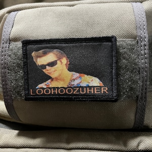 Puede incluir: Un parche en blanco y negro con una imagen de un hombre con gafas de sol y una camisa floral. El texto "LOOHOOZUH" está impreso en naranja debajo de la imagen.