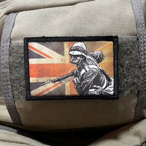 May include: A black and white patch with a soldier holding a rifle in front of a faded Union Jack flag.