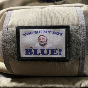 May include: A black and blue patch with a white background. The patch features a picture of a man with a white beard and the text "YOU'RE MY BOY BLUE!"