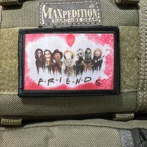 May include: A black and white patch with a pink background featuring a group of horror movie characters with a red balloon. The text "FRIENDS" is printed in black below the characters.
