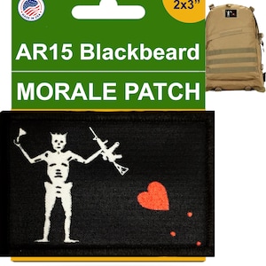 May include: Black and white morale patch featuring a skeleton holding a rifle and a red heart. The patch is 2 inches by 3 inches and says "AR15 Blackbeard" at the top.