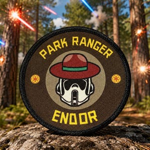 May include: A circular embroidered patch with a dark brown border and a tan center. It features a white scout trooper helmet wearing a red ranger hat with a green band. The text reads PARK RANGER at the top and ENDOR at the bottom in yellow.