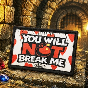 May include: A rectangular embroidered patch with a black border featuring a white background, red heart shapes, and the bold black text "YOU WILL NOT BREAK ME" with a red bomb graphic replacing the letter "O" in the word "NOT".